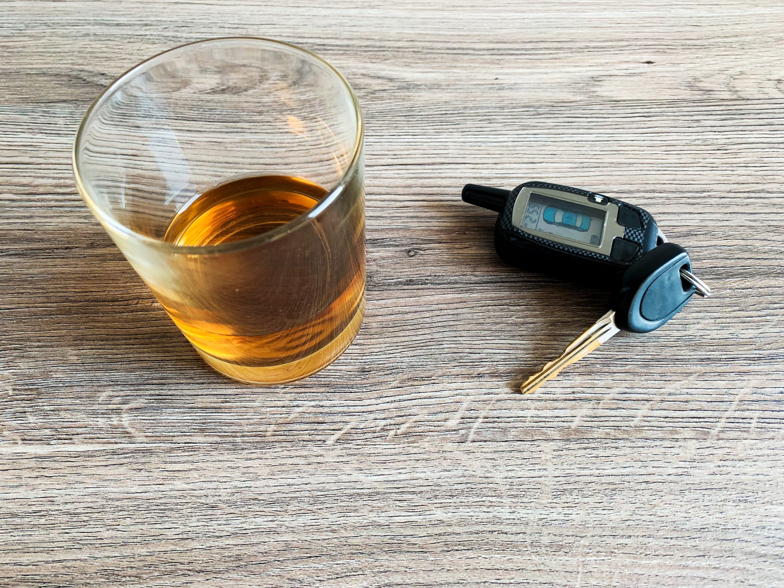 a glass of alcohol beside car keys