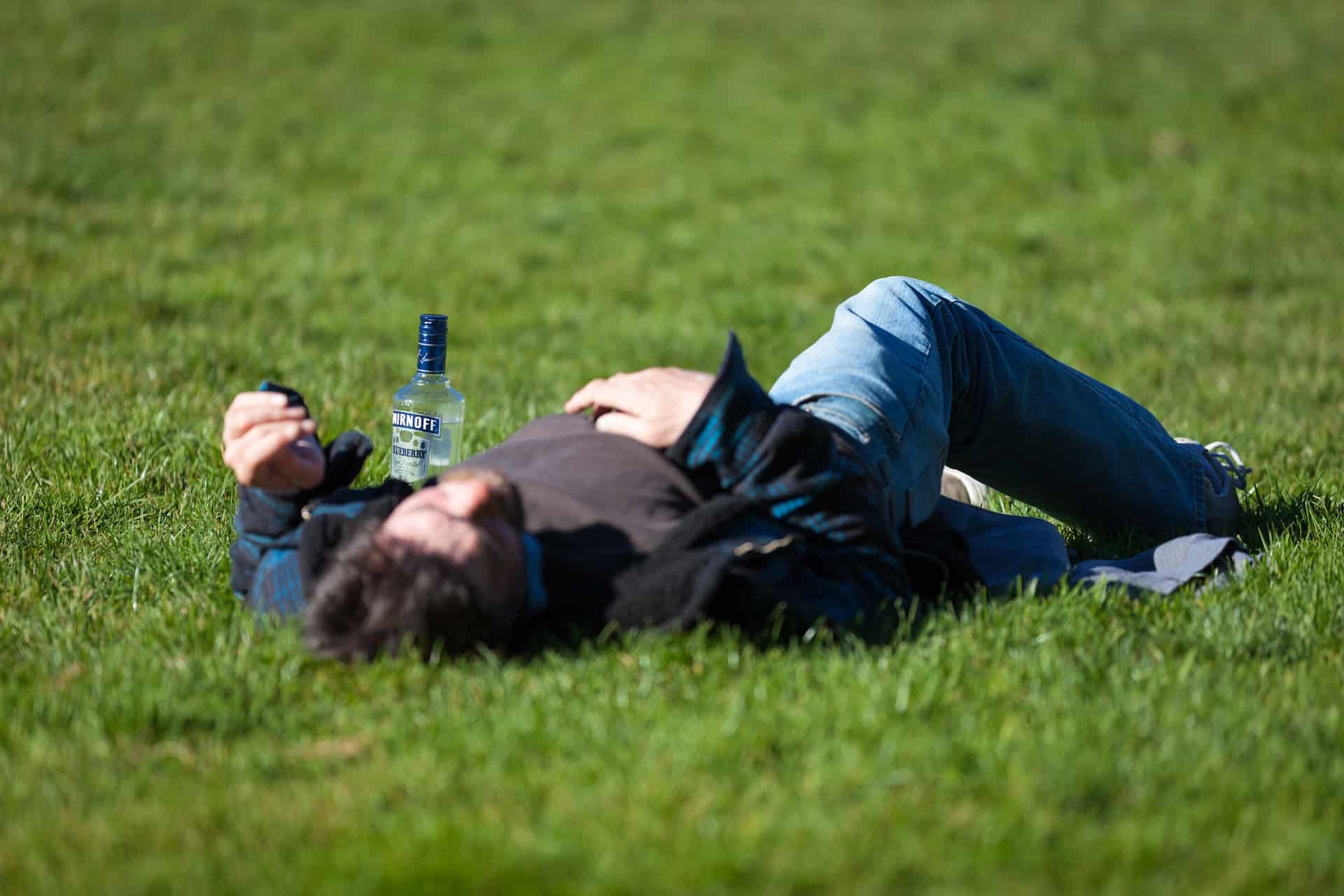 person with alcohol lying on the grass